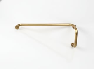 Brass towel bar with rounded ends mounted on white wall