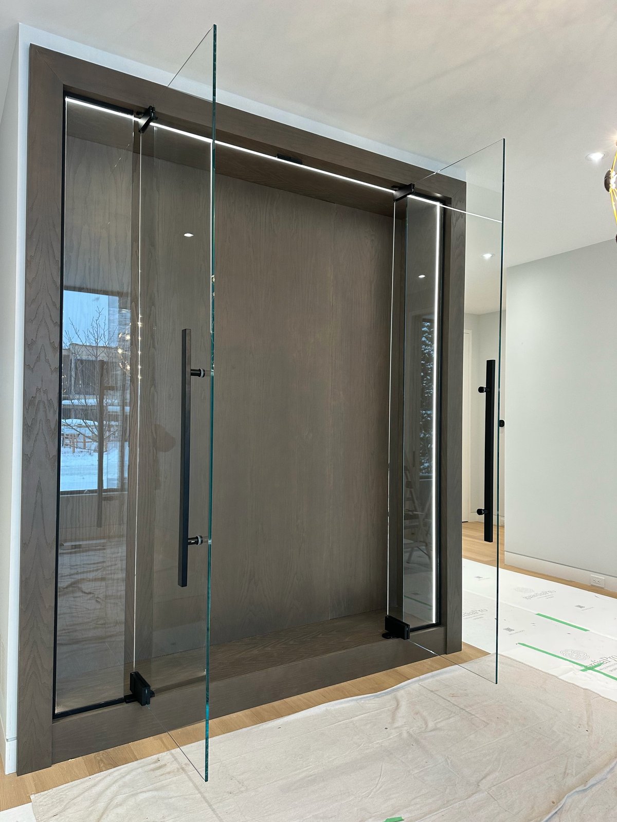 Modern frameless glass shower enclosure with dark tile walls and black hardware in a contemporary bathroom