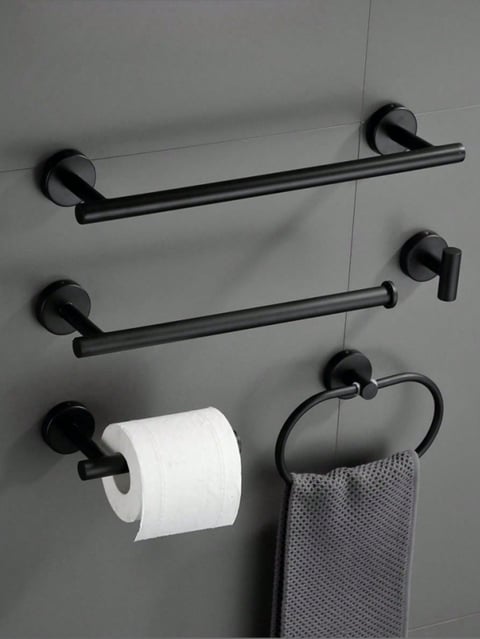 Black bathroom hardware mounted on gray wall including towel bars, toilet paper holder, and towel ring with a gray towel
