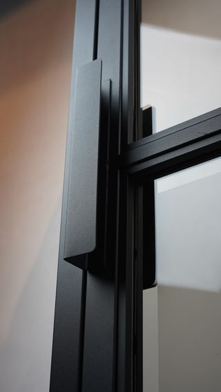 Close-up of black metal door frame with modern handle and glass panel details