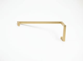 Gold-toned metal cabinet handle with angular L-shape design on white background